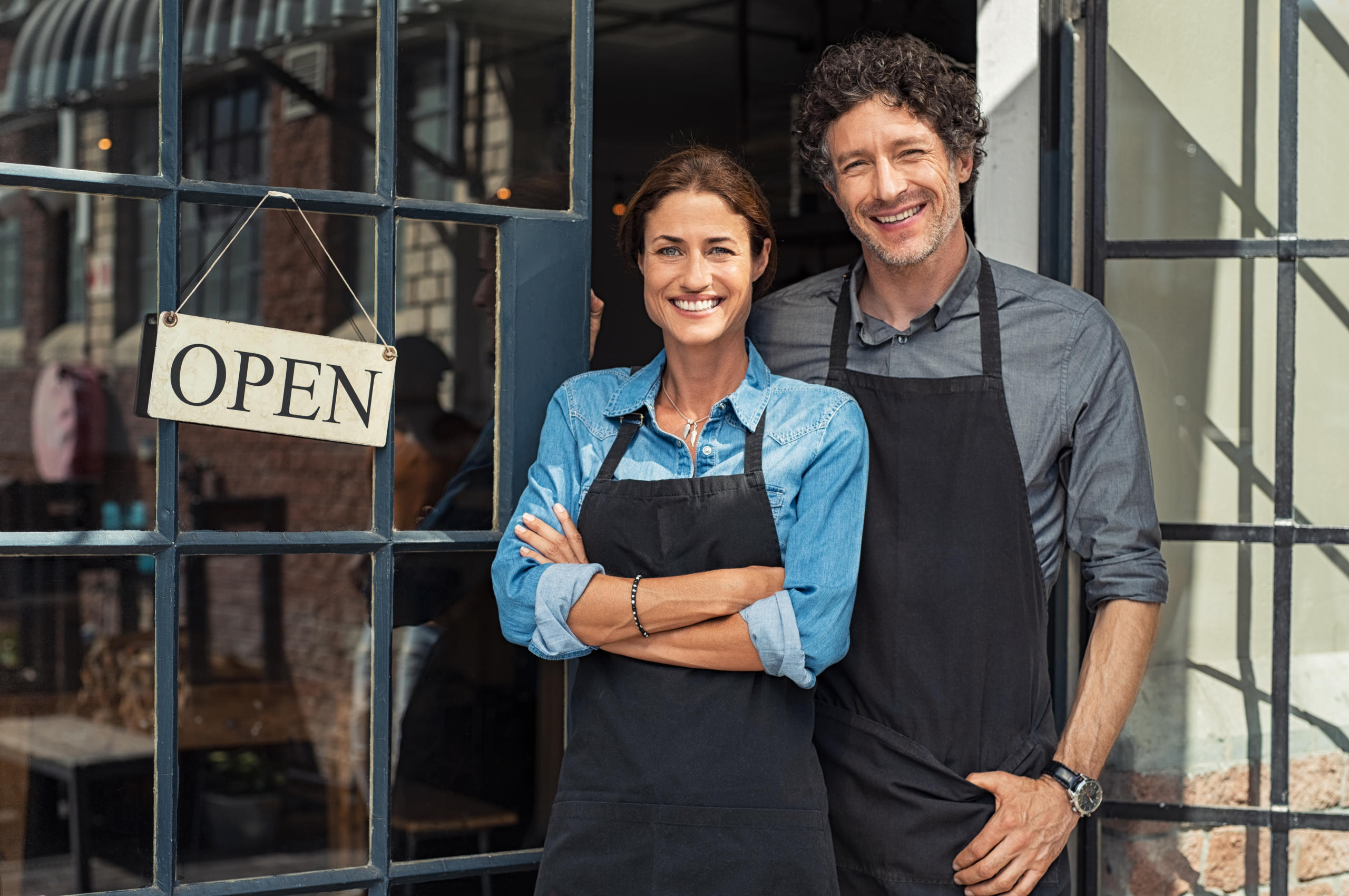 two small business owners smiling in front of their business after getting an E-2 visa