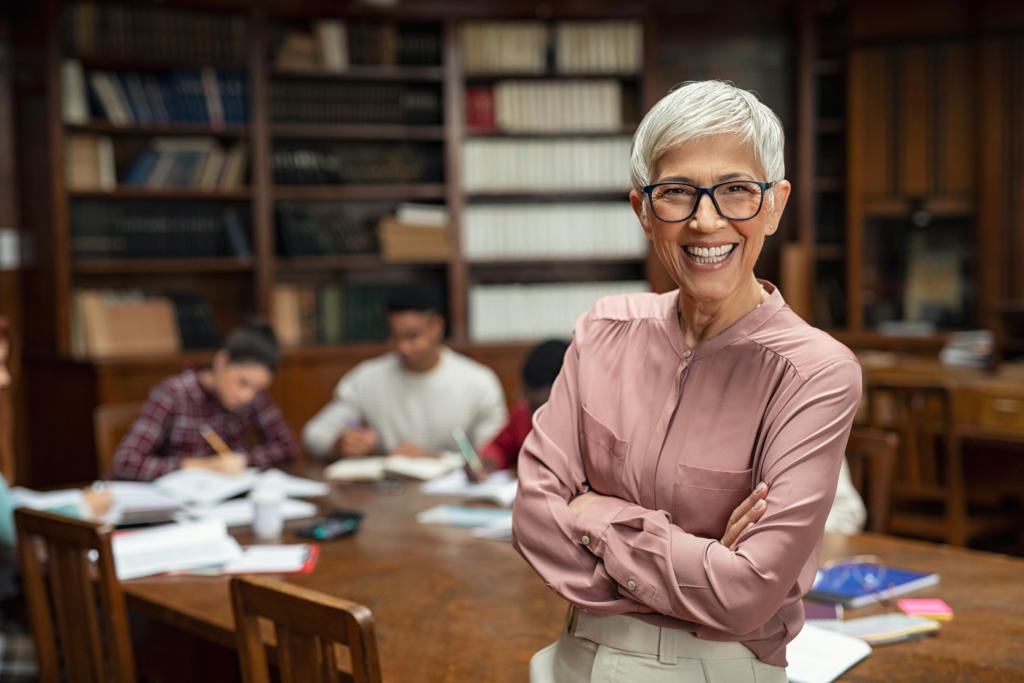 woman in library smiling with student in background