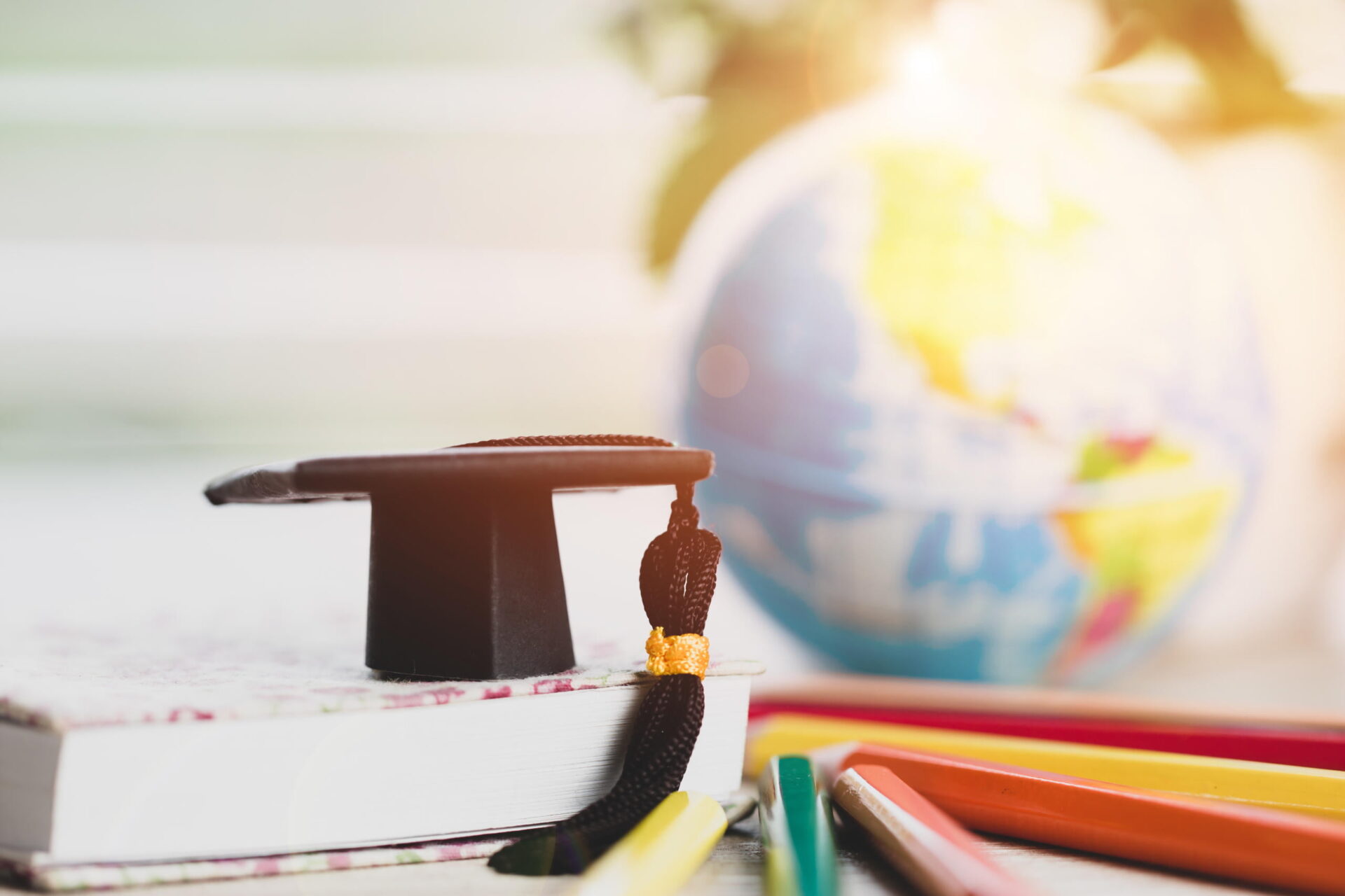 illustration of books globe and colored pencils with graduation cap