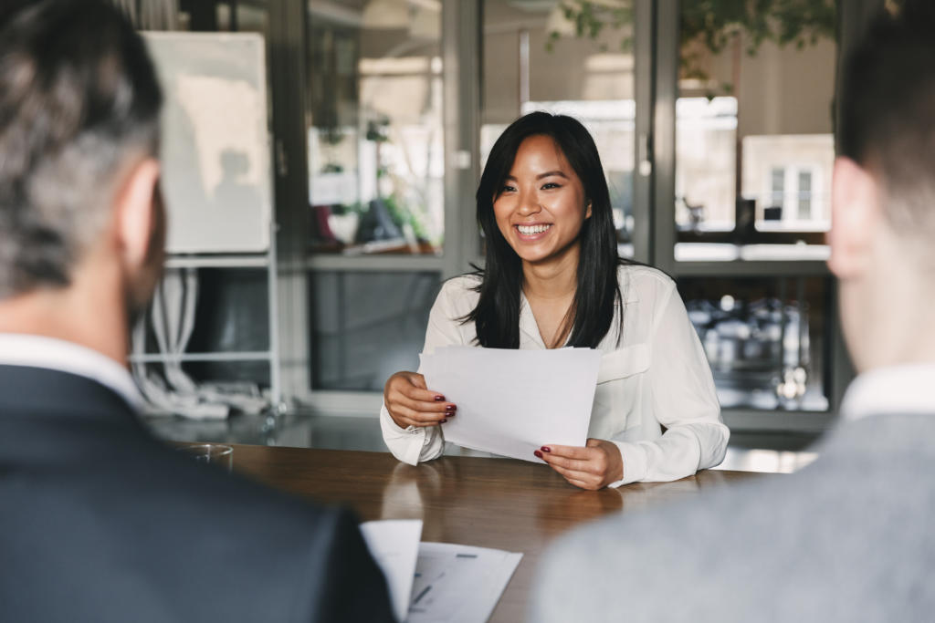 young asian woman smiling and holding resume having a job interview