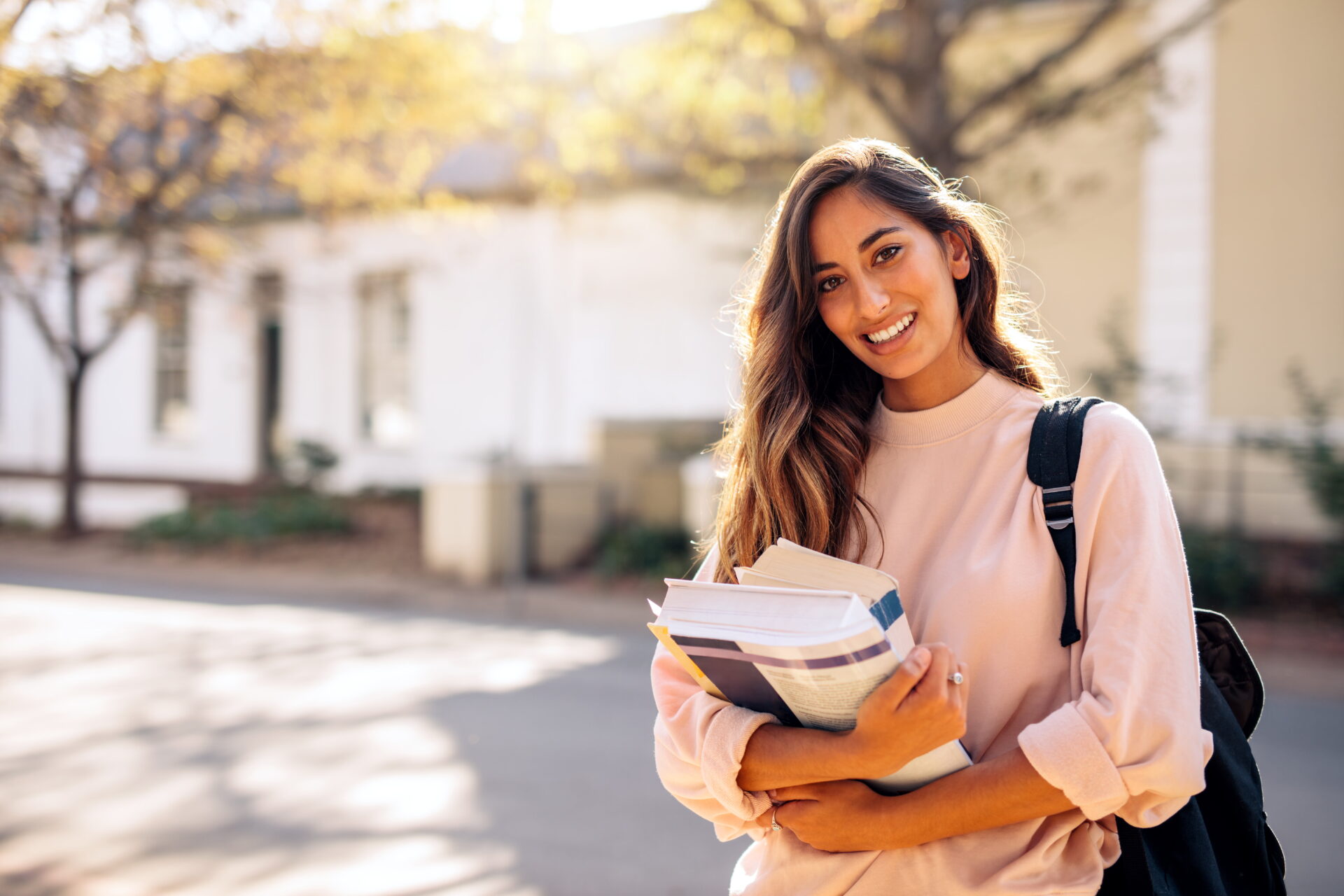 latino woman holding books and backpack at school