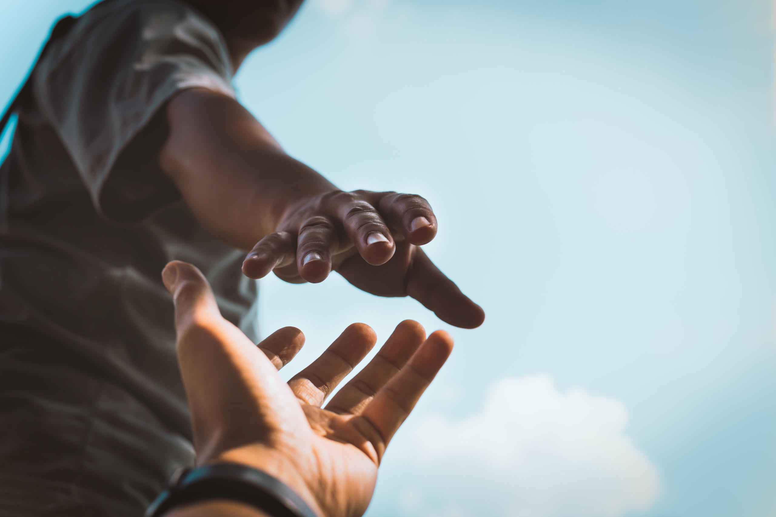 closeup of hand reaching out to another hand offering assistance